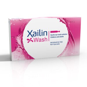 A product packaging for “Xailin Wash,” which is a sterile eye wash solution for children and adults. The box is predominantly white with a splash of pink liquid depicted on the front, symbolizing the eye wash. It’s labeled as preservative-free and non-injectable, with 20 single-dose containers inside. The brand VISUfarma is also visible at the bottom right corner.